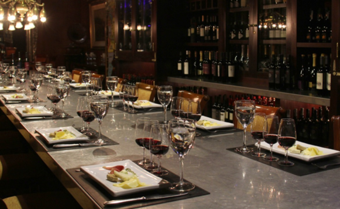Mesa preparada para una degustación de vinos, con copas y porciones individuales de acompañamientos.