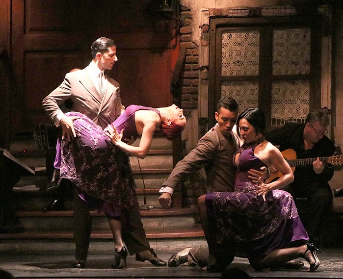 Dos parejas de bailarines durante un espectáculo en Aljibe Tango, con un músico al fondo.