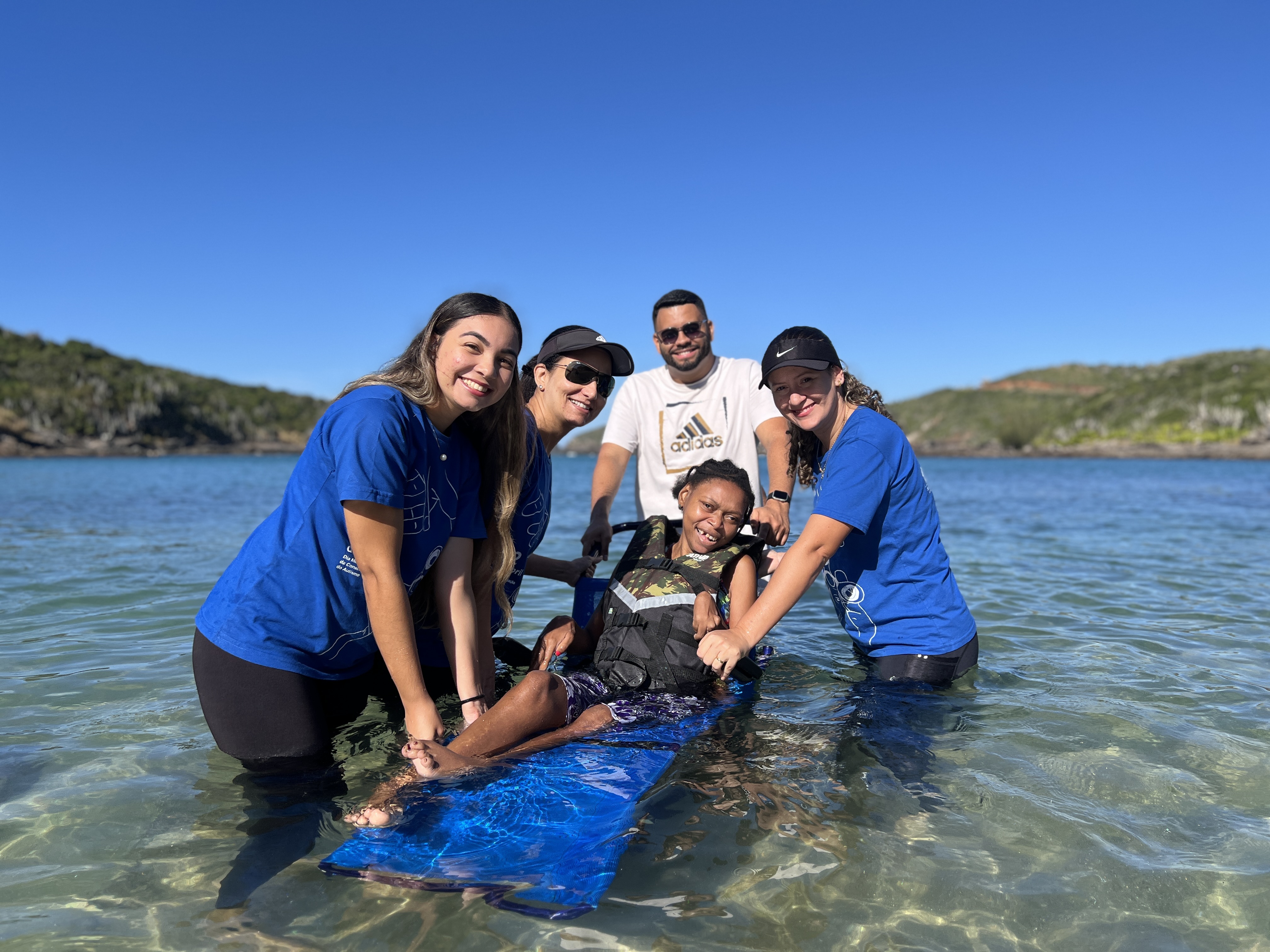 Equipe do Projeto Mar para Todos auxilia participante durante banho de mar acessível em Búzios.