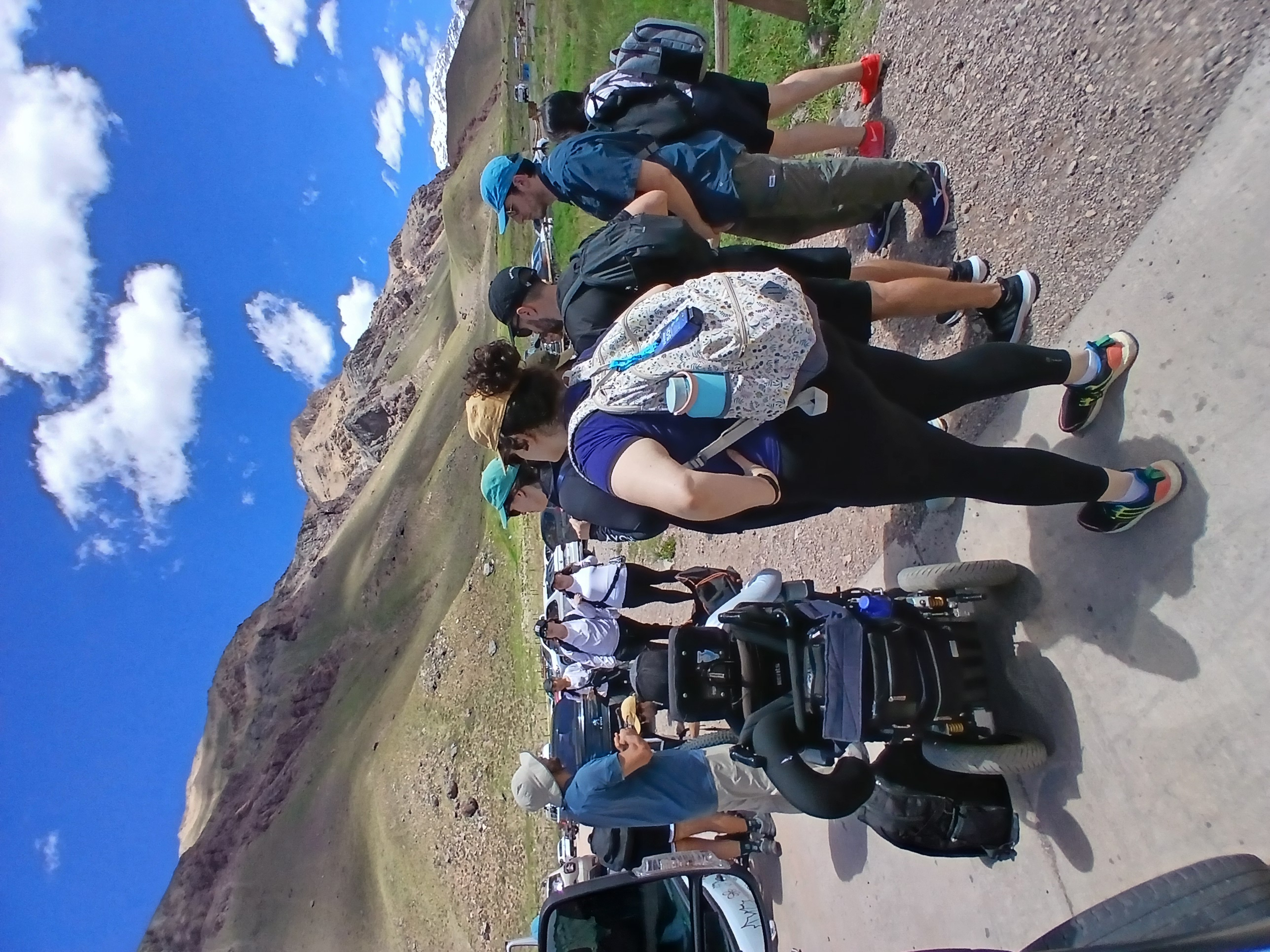 Grupo de visitantes, incluida una persona en silla de ruedas, junto a vehículos entre las montañas del Parque Aconcagua.