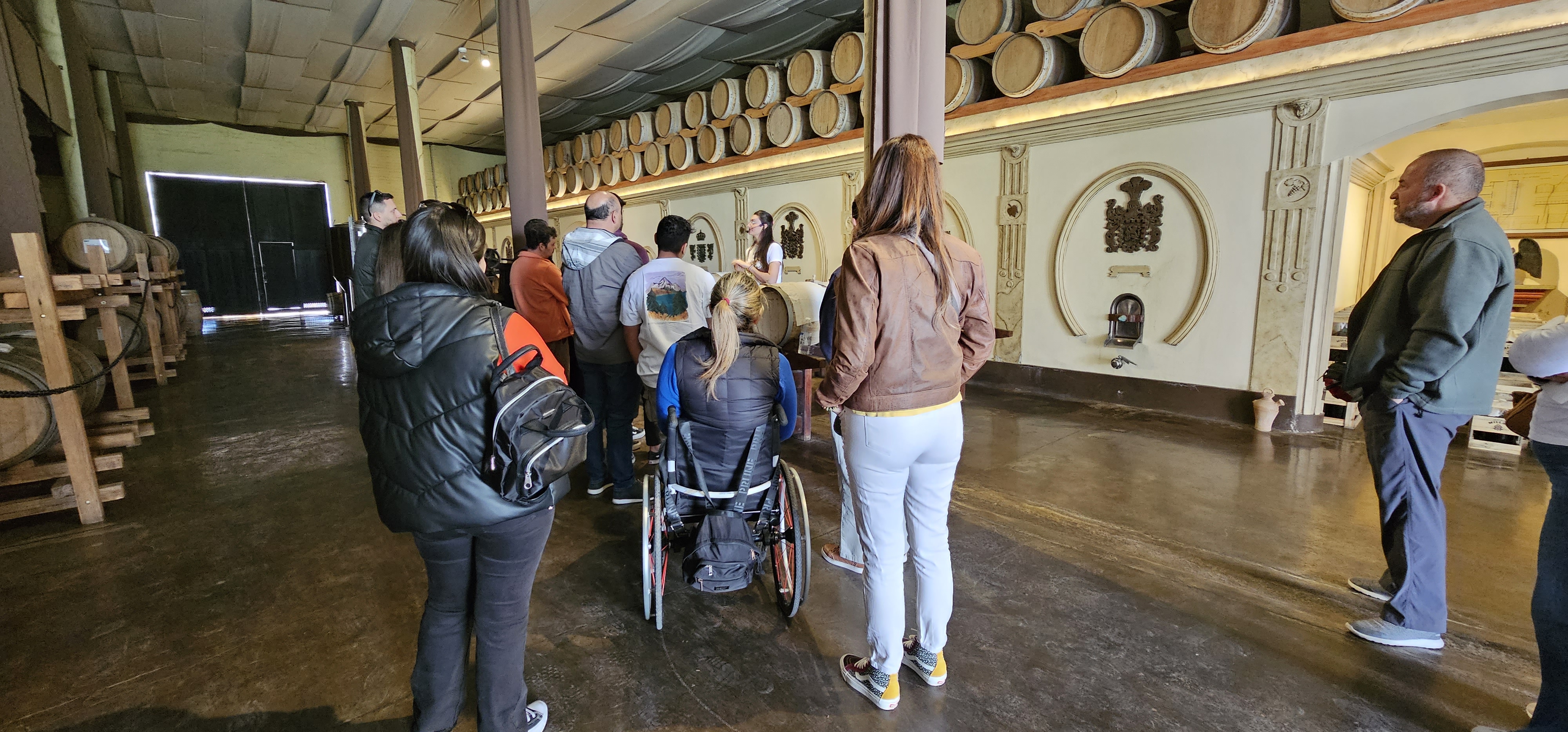 A group of visitors, including a woman using a wheelchair, takes a guided tour at Laur olive oil producer in Mendoza.