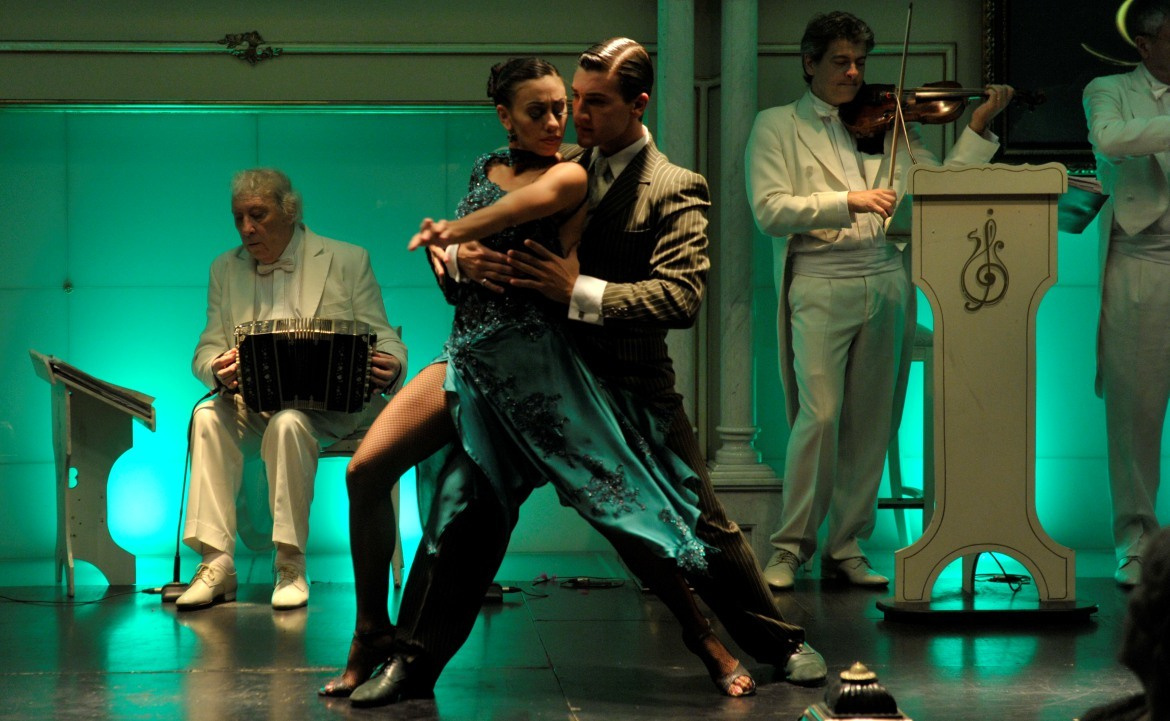 Couple dancing tango at Gala Tango, accompanied by bandoneon and violin players.