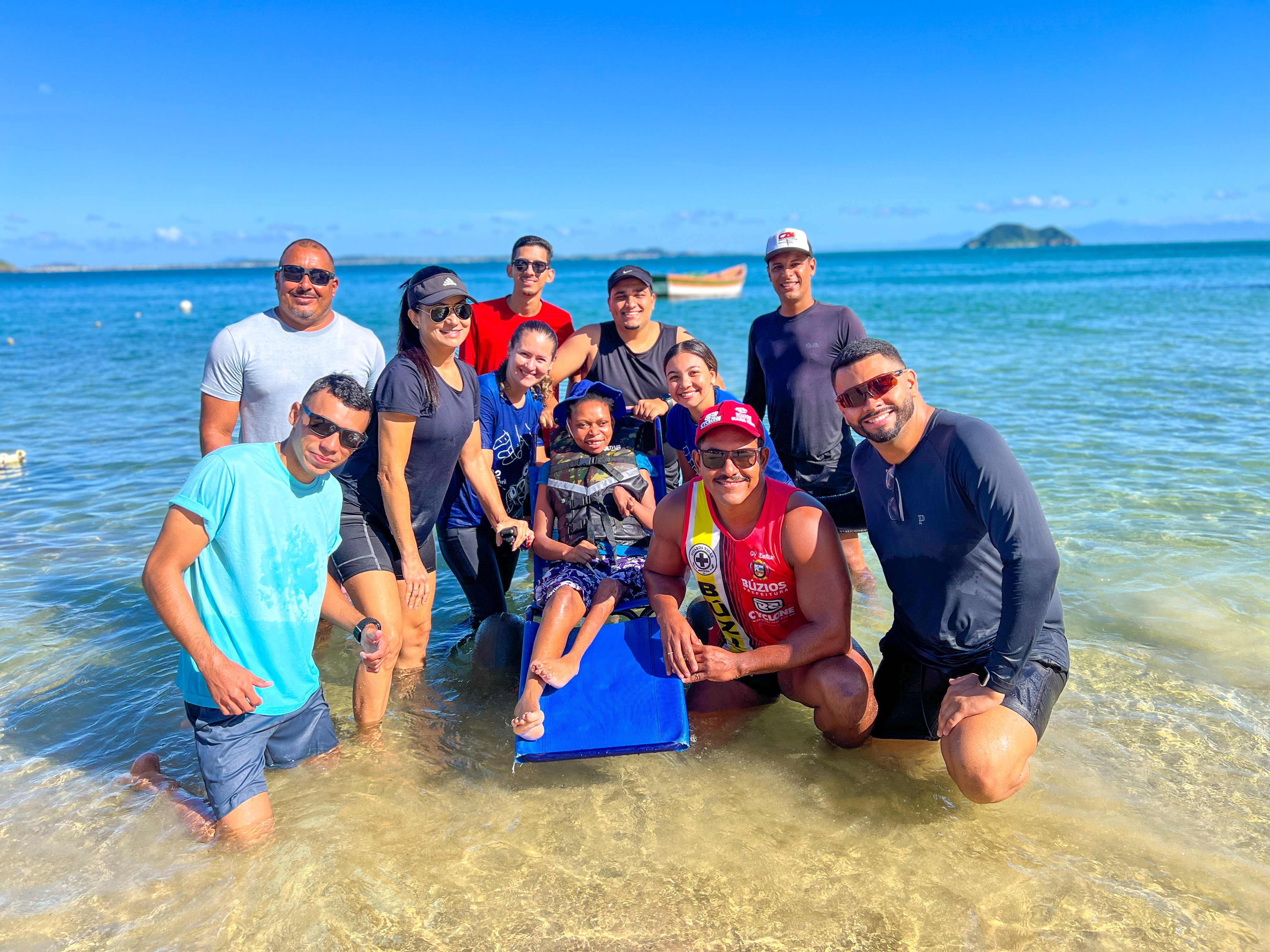 Participant using an amphibious beach wheelchair accompanied by the Mar para Todos project team in Búzios.