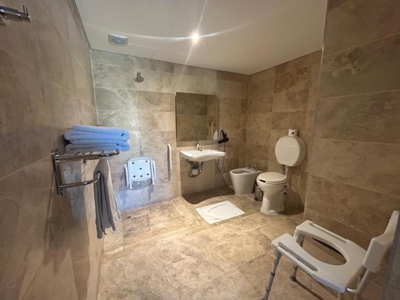 Bathroom at Mod Hotel Mendoza with a level-access shower, a folding seat, grab bars and a shower chair.