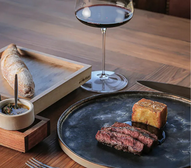 A meat dish with a side and a glass of wine at Angélica Cocina Maestra at Bodega Catena Zapata.